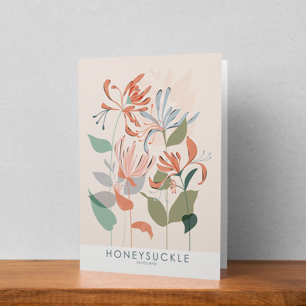 A greeting card featuring a honeysuckle illustration stood up against a pale background. The text on the illustration reads honeysuckle lonicera