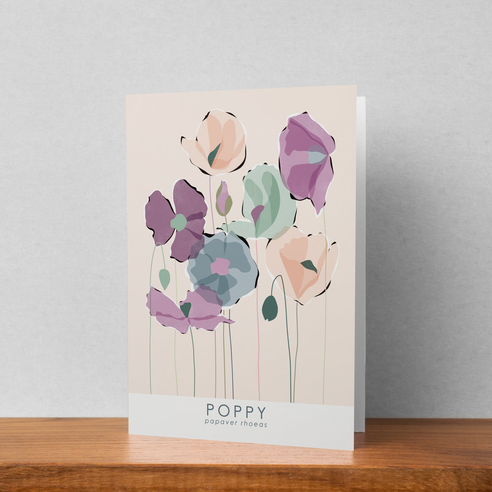 A greeting card featuring a poppy illustration stood up against a pale background. The text on the illustration reads poppy papaver rhoeas