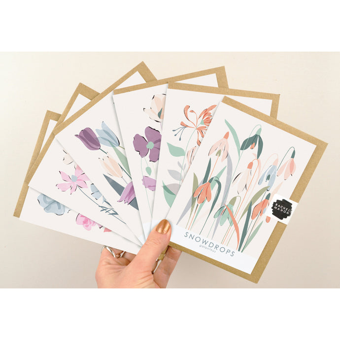 6 floral greeting cards held up in a fan formation against a pale background