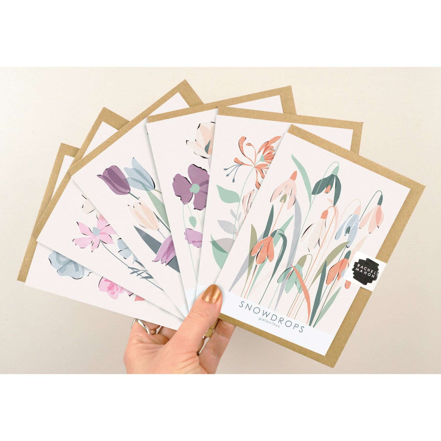 6 floral greeting cards held up in a fan formation against a pale background